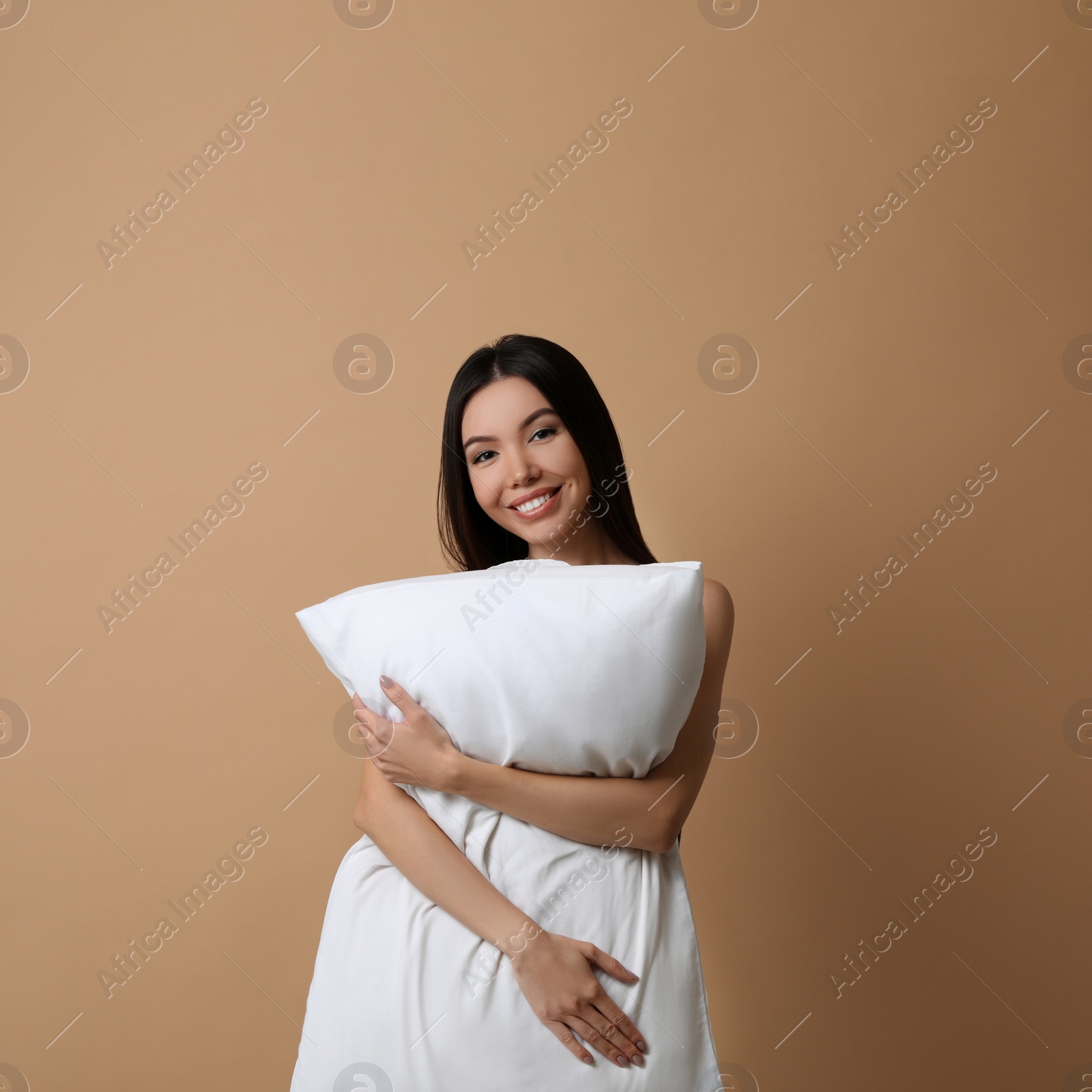 Photo of Beautiful Asian woman with pillow on beige background. Bedtime