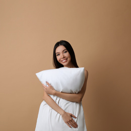 Photo of Beautiful Asian woman with pillow on beige background. Bedtime