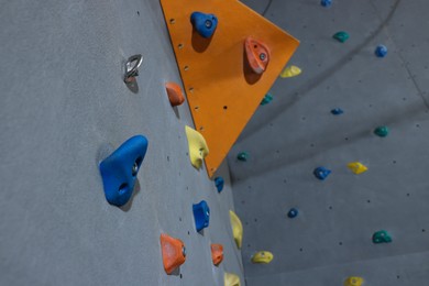 Photo of Climbing wall with holds in gym, low angle view. Extreme sport