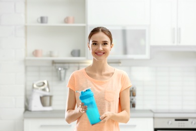 Athletic young woman with protein shake in kitchen