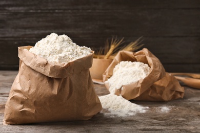 Photo of Paper bags with flour on wooden table