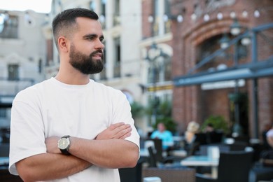 Photo of Portrait of handsome bearded man on city street. Space for text