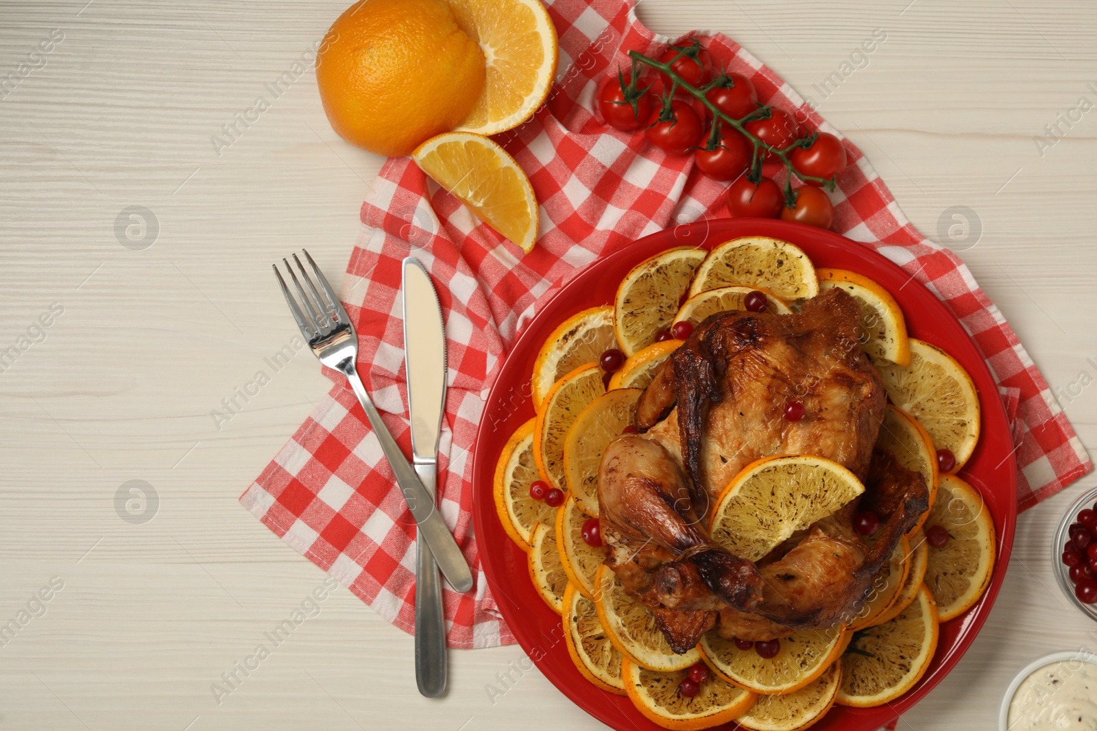 Photo of Baked chicken with orange slices served on white wooden table, flat lay