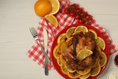 Photo of Baked chicken with orange slices served on white wooden table, flat lay