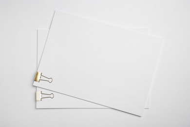 Photo of Sheets of paper with clips on white background, top view