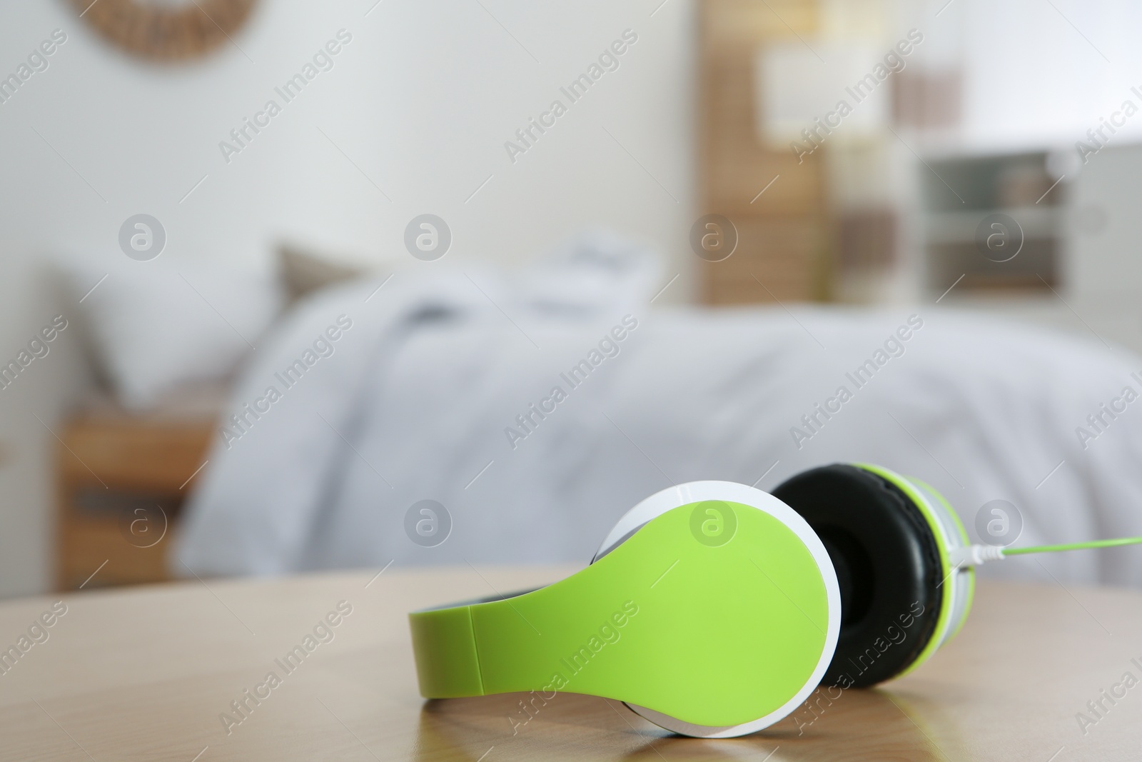 Photo of Stylish modern headphones with earmuffs on table against blurred background, space for text