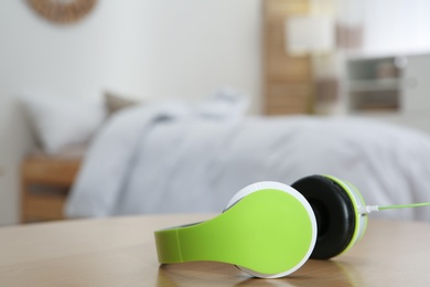 Photo of Stylish modern headphones with earmuffs on table against blurred background, space for text