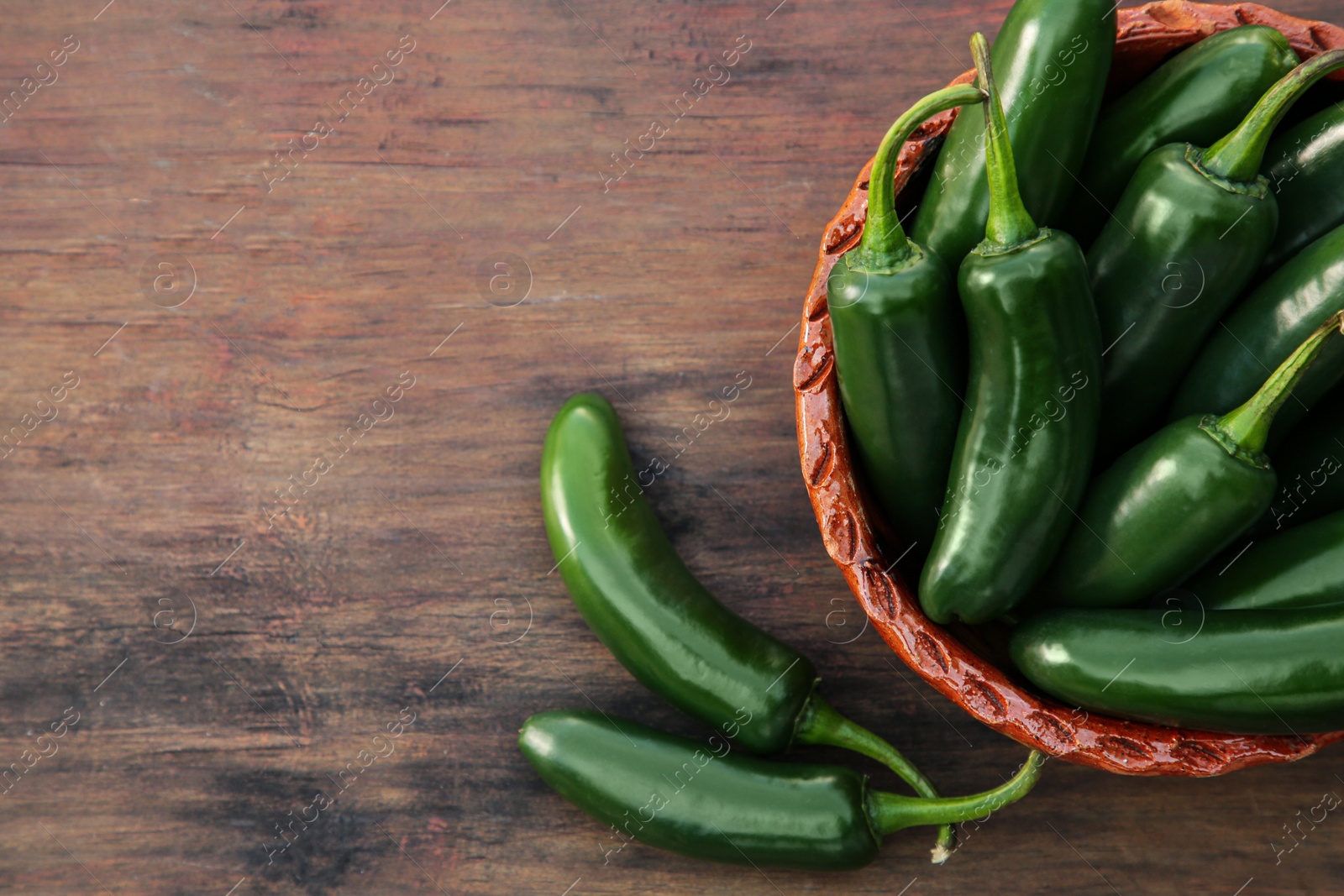 Photo of Green jalapeno peppers on wooden table, flat lay. Space for text