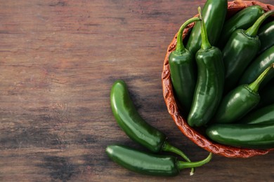Photo of Green jalapeno peppers on wooden table, flat lay. Space for text
