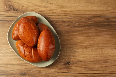 Photo of Delicious baked pirozhki on wooden table, top view. Space for text
