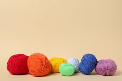 Photo of Soft colorful woolen yarns on beige background, space for text