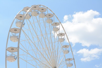 Photo of Large white observation wheel against blue cloudy sky