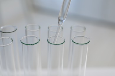 Laboratory analysis. Dripping liquid into test tubes indoors, closeup