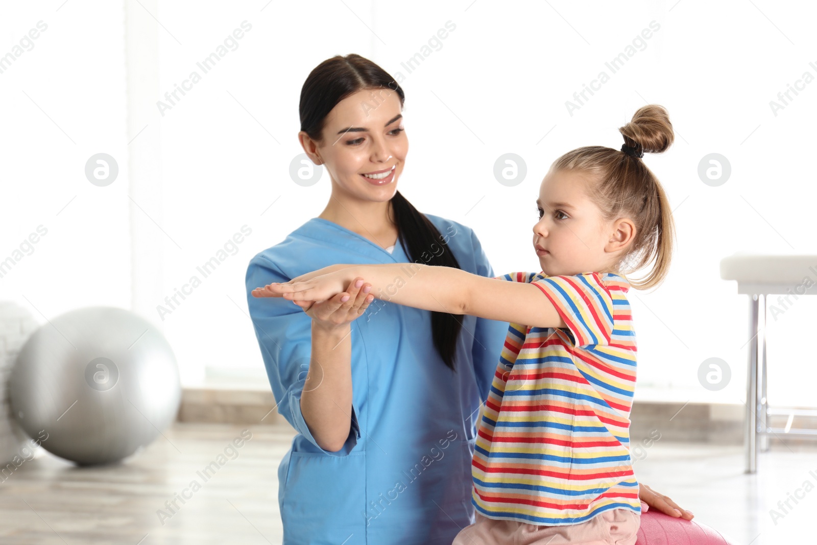 Photo of Orthopedist working with little girl in hospital gym