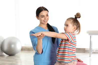 Photo of Orthopedist working with little girl in hospital gym