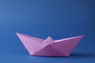 Photo of Handmade violet paper boat on blue background. Origami art