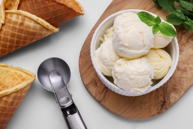 Photo of Bowlice cream, cones and mint leaves on white table, flat lay