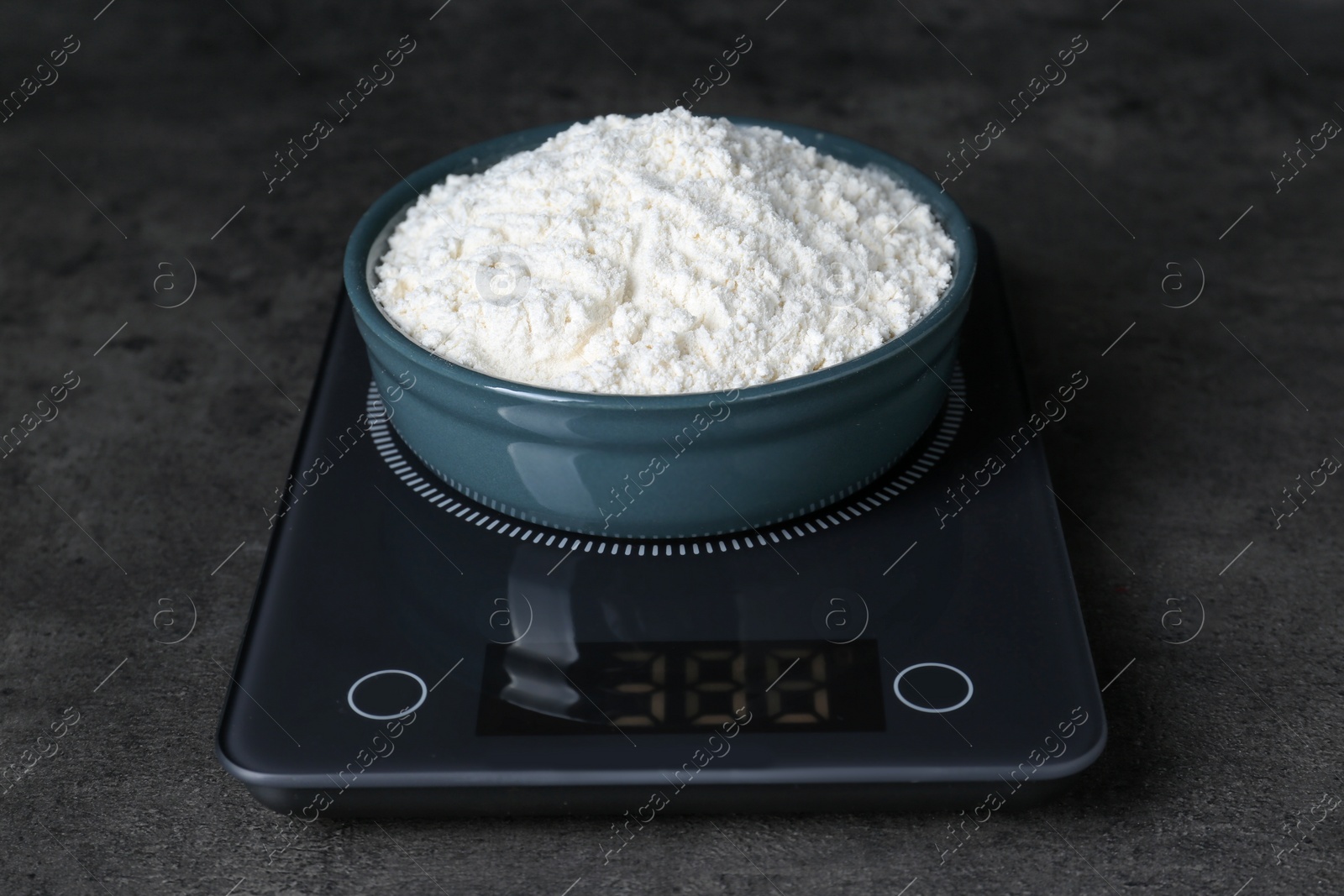 Photo of Electronic scales with flour on black table