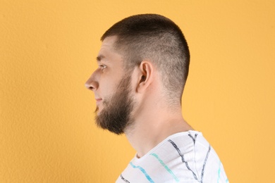 Young man with hearing problem on color background