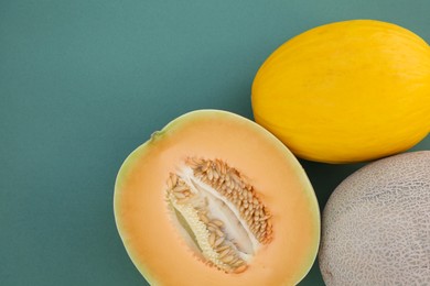Photo of Different tasty ripe melons on teal background, flat lay. Space for text