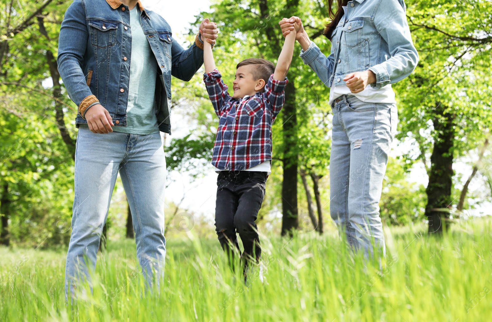 Photo of Cute little child having fun with his parents in park. Family weekend