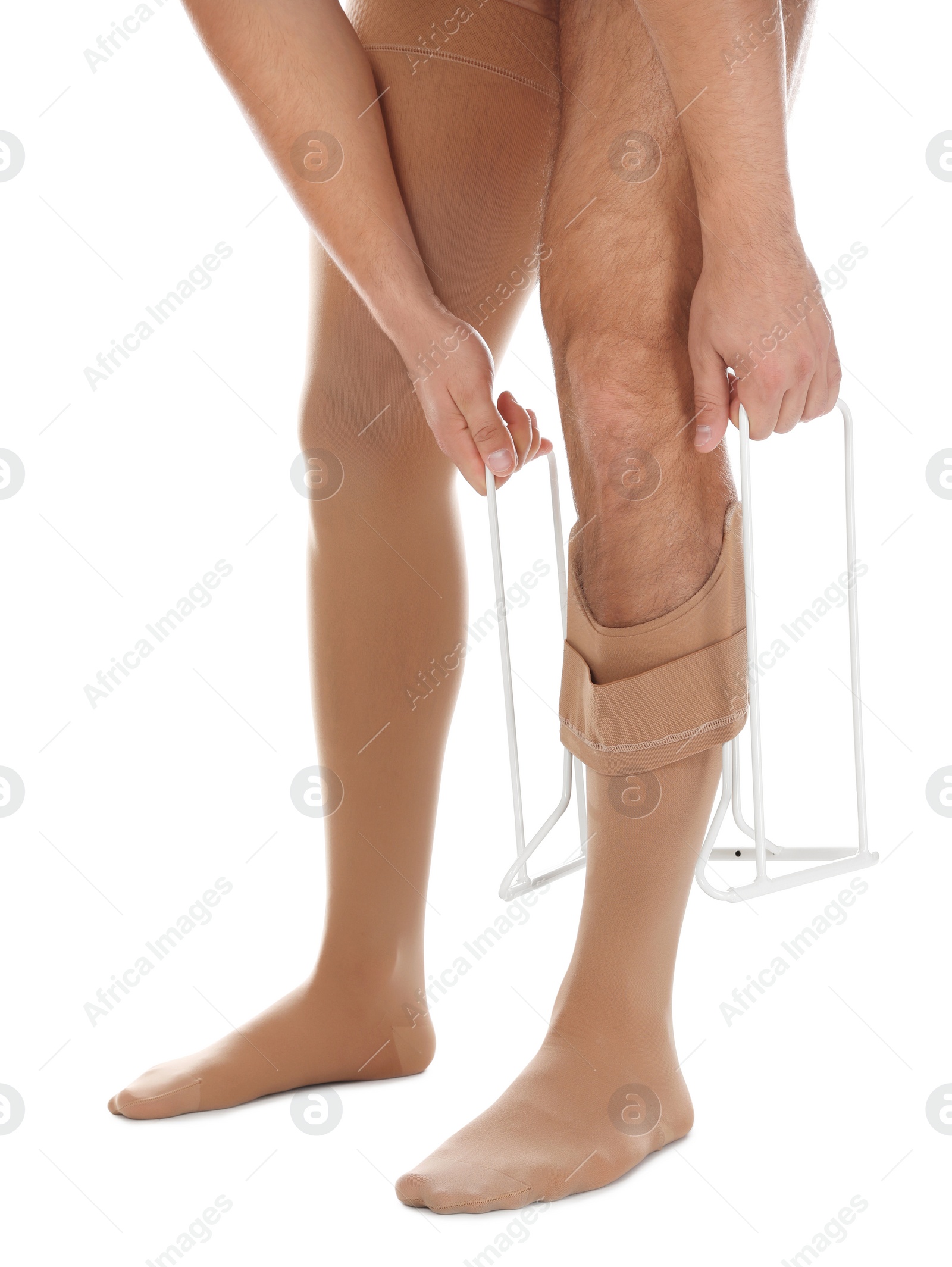 Photo of Man putting on compression garment with stocking donner against white background, closeup