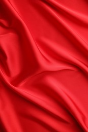 Crumpled red silk fabric as background, top view