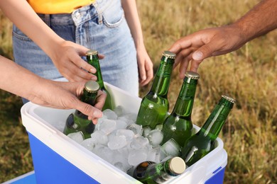 Photo of Friends taking bottles of beer from cool box outdoors, closeup