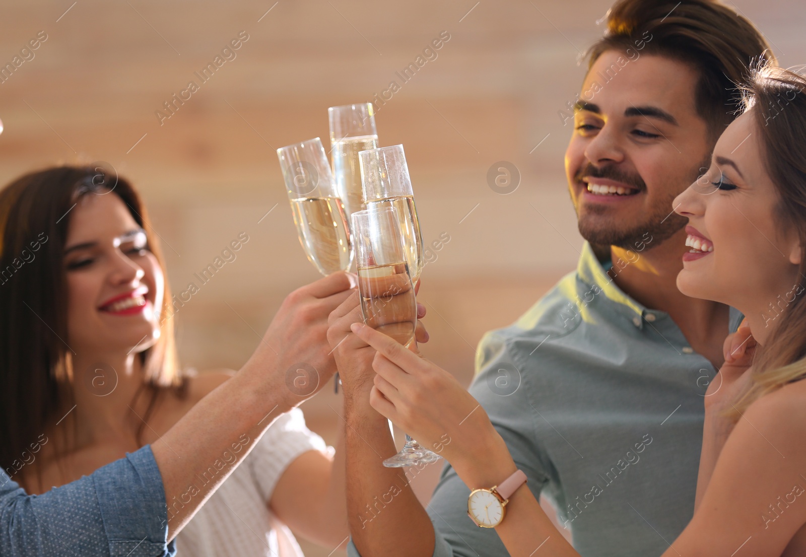 Photo of Friends clinking glasses with champagne at party indoors