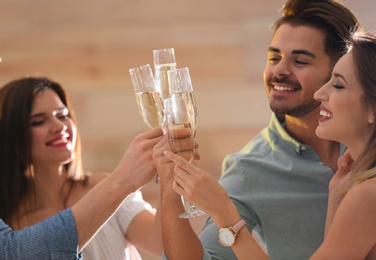 Friends clinking glasses with champagne at party indoors