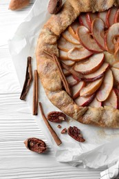 Photo of Delicious apple galette, cinnamon and pecans on white wooden table, flat lay