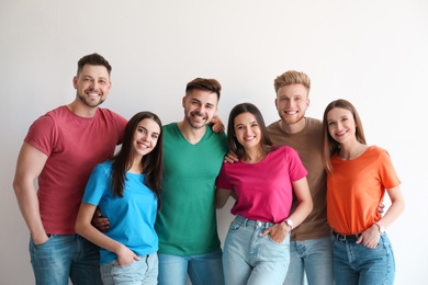 Group of happy people posing near light wall