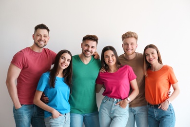 Photo of Group of happy people posing near light wall