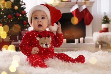 Photo of Baby in Santa hat and bright Christmas pajamas on floor at home