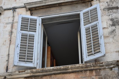 Old residential building with open window and wooden shutters