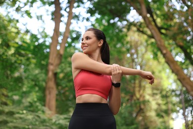 Beautiful woman in sportswear stretching in park