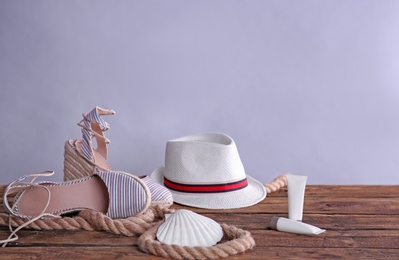 Beach objects on wooden table against color background