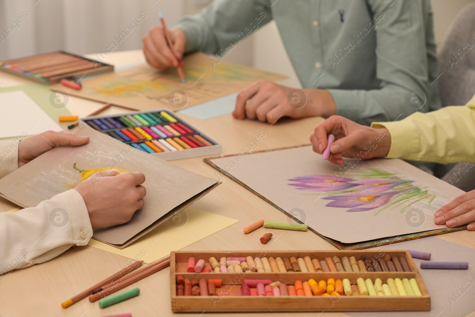 Photo of Artists drawing with soft pastels and pencils at table, closeup