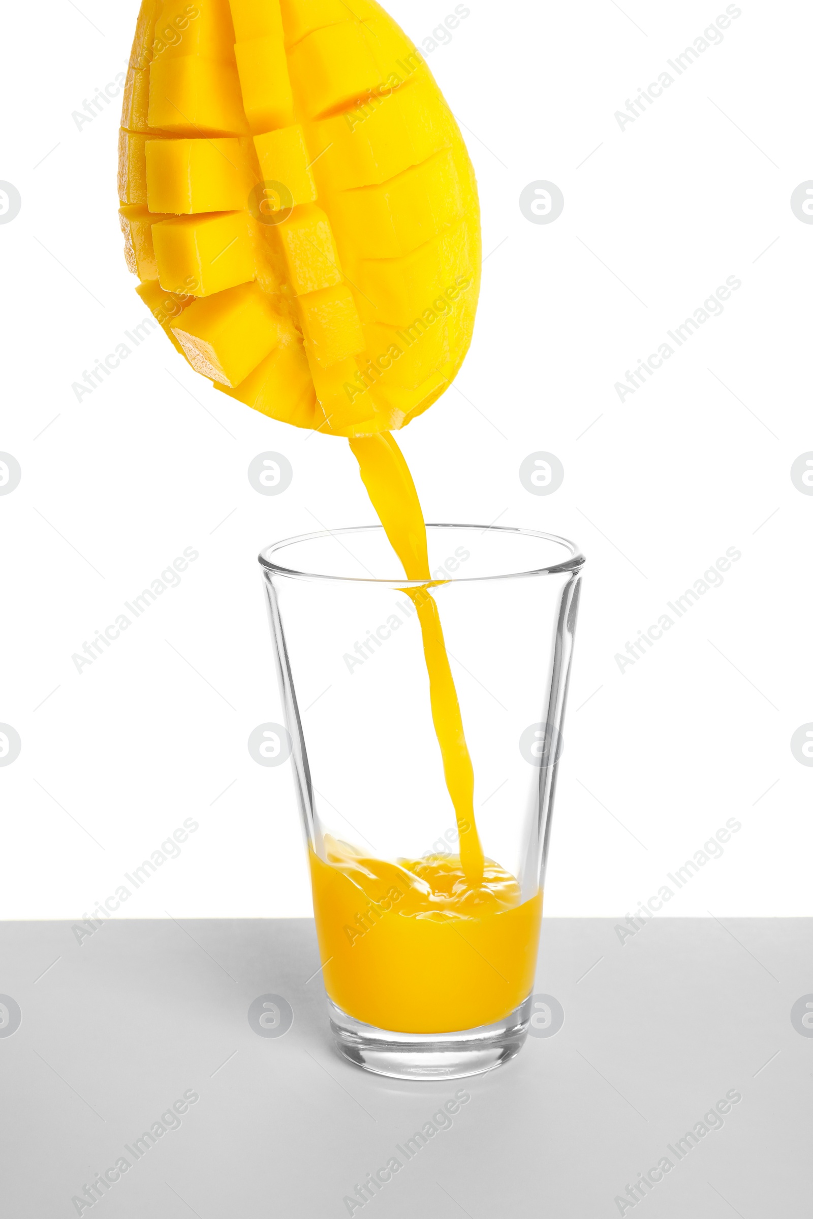 Image of Making mango fresh. Juice pouring from mango into glass on white background