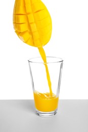 Image of Making mango fresh. Juice pouring from mango into glass on white background