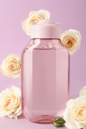 Photo of Bottle of micellar water and beautiful roses on light pink background