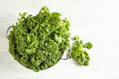 Photo of Fresh kale leaves on white wooden table, flat lay