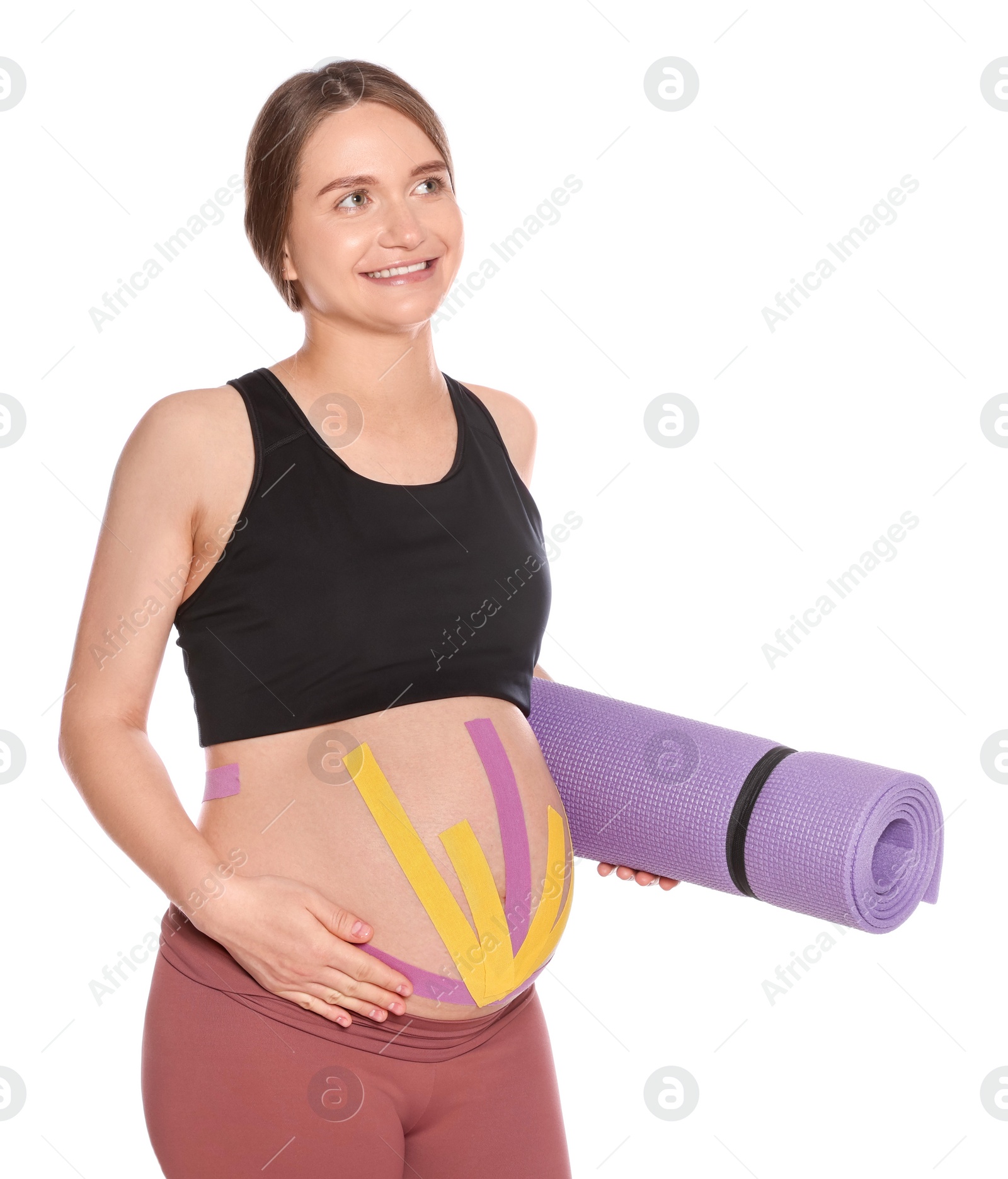 Photo of Sporty pregnant woman with kinesio tapes holding yoga mat on white background