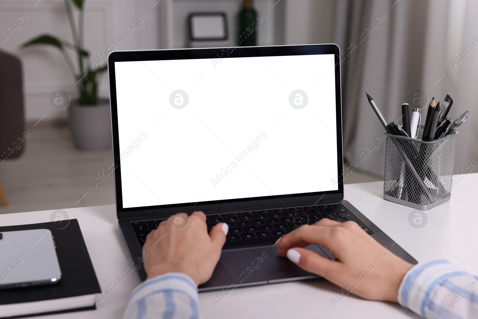 Photo of Woman working with laptop at white desk indoors, closeup