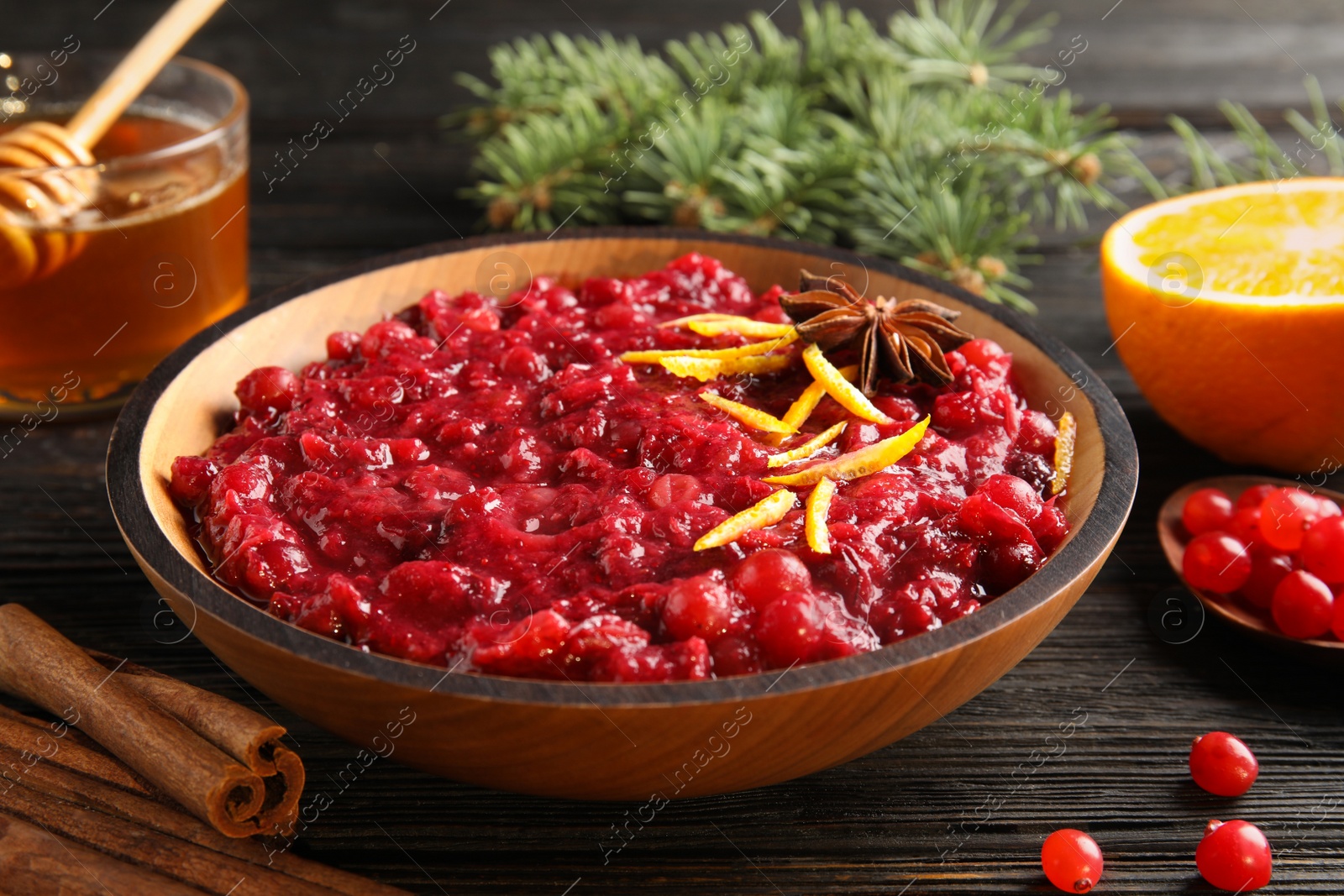 Photo of Plate of tasty cranberry sauce with citrus zest and anise on table, closeup