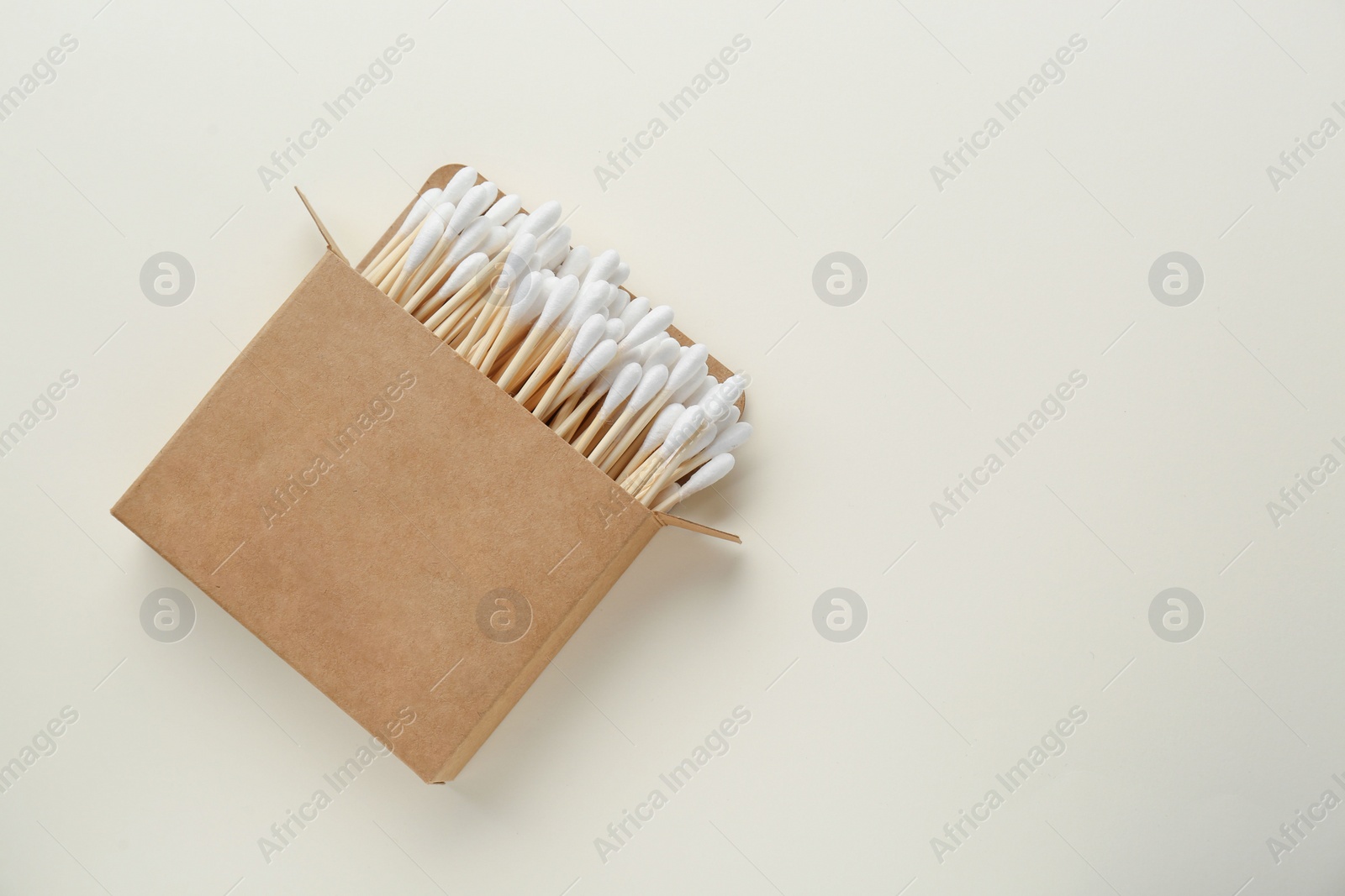 Photo of Box with wooden cotton buds on beige background, top view. Space for text