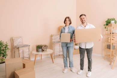 Photo of Happy couple with moving boxes in new apartment