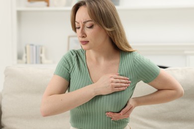 Photo of Mammology. Young woman doing breast self-examination at home