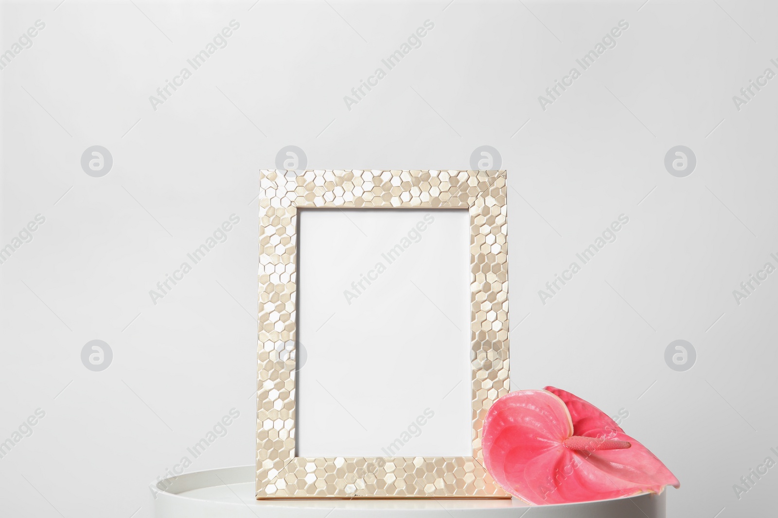 Photo of Blank frame and flower on table against white background. Mock up for design