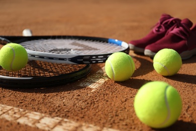 Photo of Tennis balls, rackets and shoes on clay court, closeup